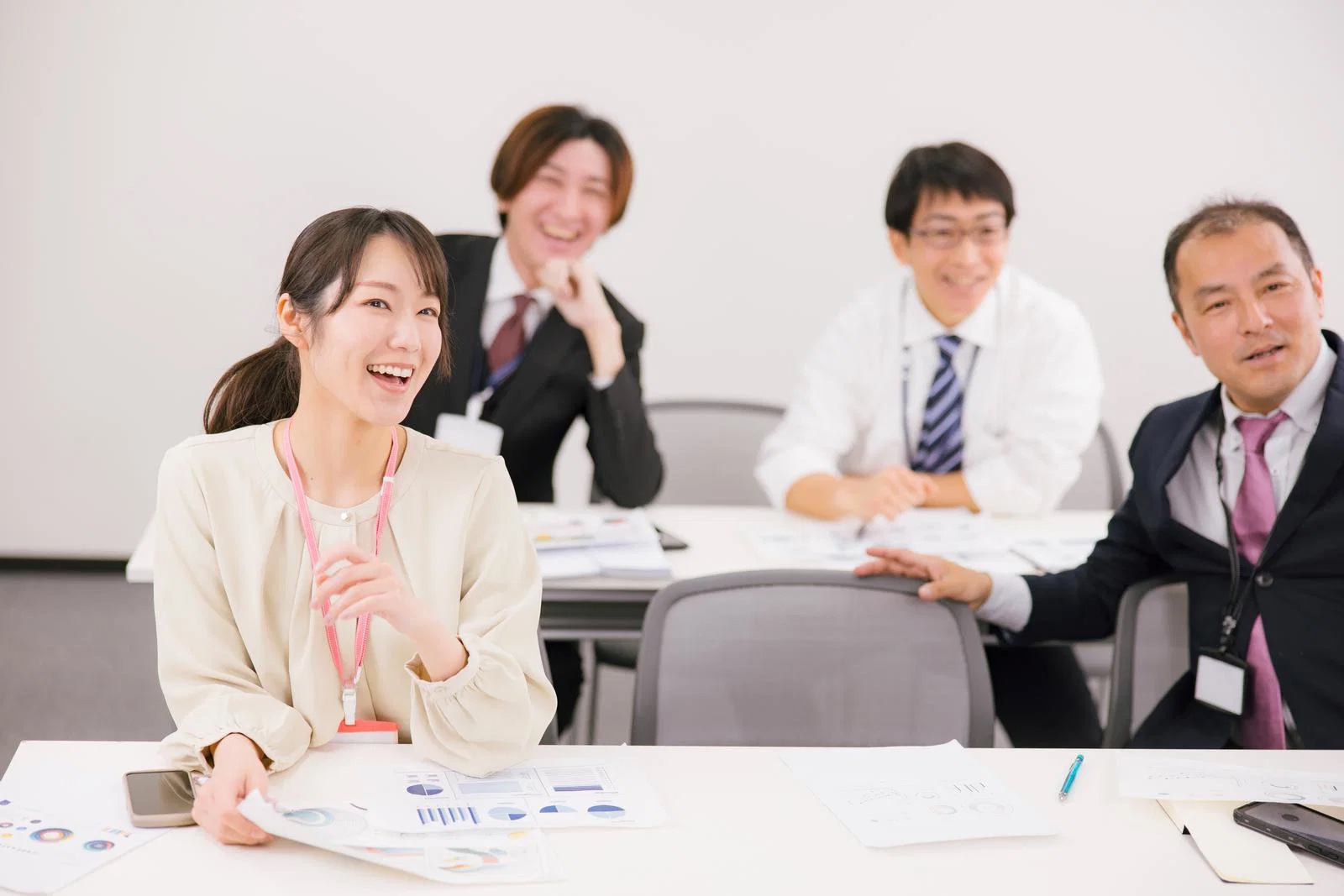 机を囲んで笑顔でミーティングするチーム